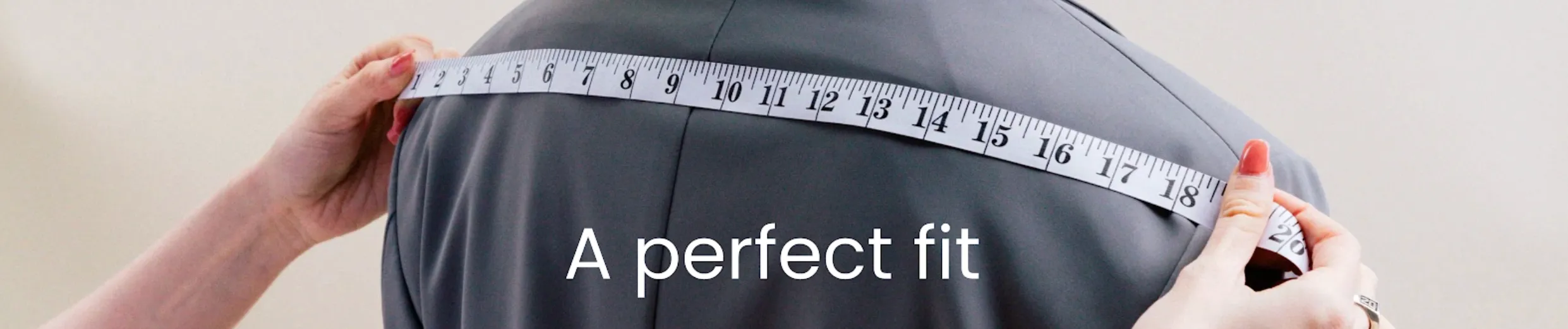 A tape measure held across the shoulders of a grey tailored garment, captioned “A perfect fit”
